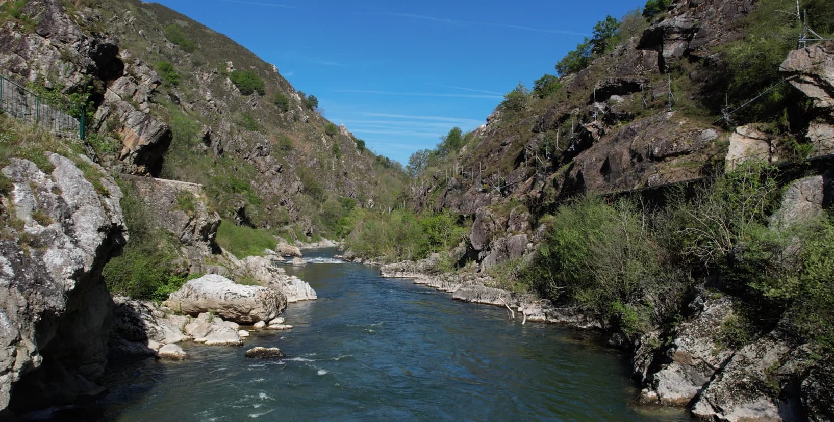 Pas de Roland - River flowing between rocky cliffs covered with vegetation under a clear blue sky.
Turnkey bike holidays from The Family Bike.